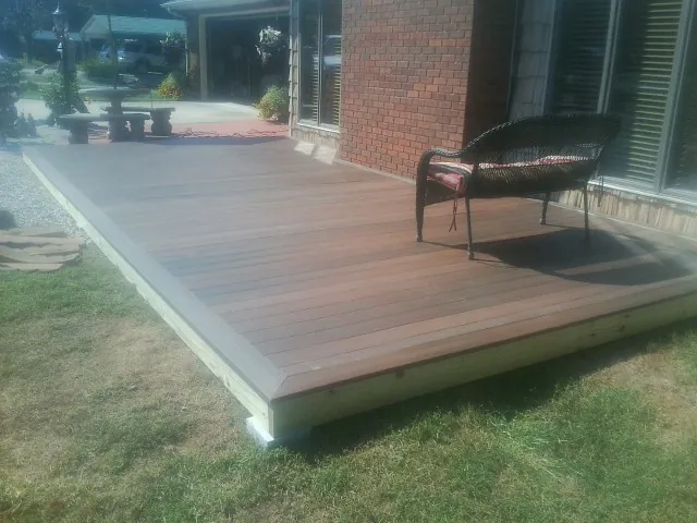 New wood deck and wicker chair beside a brick house in Sumner