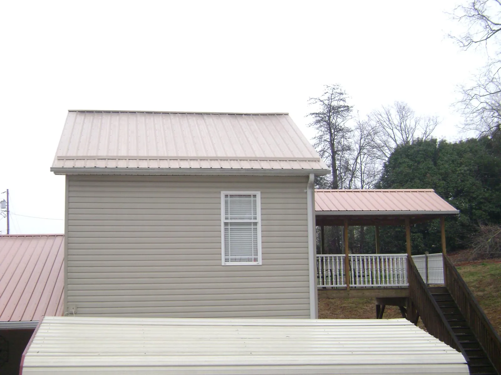 Tan metal roofs on a two story addition and attached porch, from a Roof Replacement job in Sumner